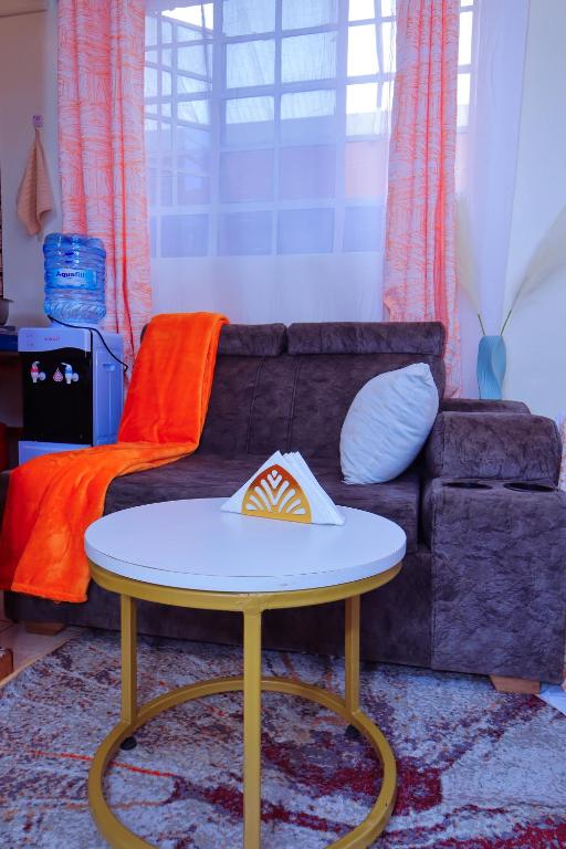 a living room with a table and a couch at Manta homes studio Apartments in Thika