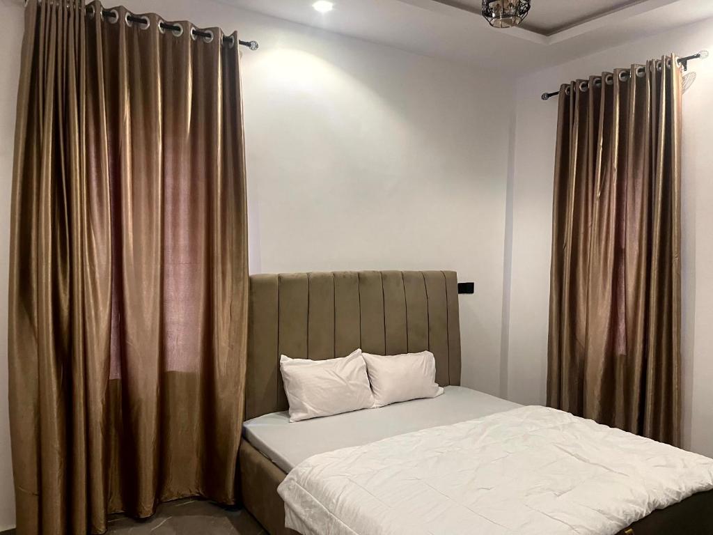 a bedroom with a bed and curtains in a room at Universal Apartment & Suites in Ibadan