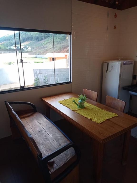 a table and a chair in a room with a window at Lar temporário Rê Auer in Santa Teresa