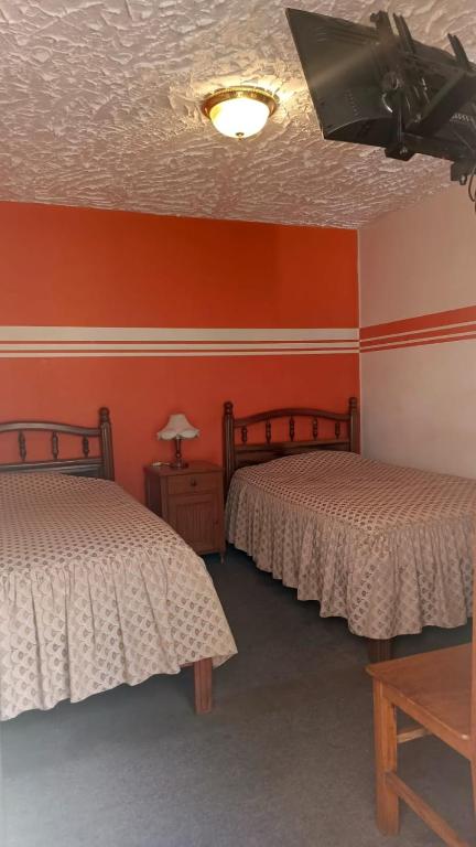two beds in a room with orange walls at Hostal Churuquella in Sucre