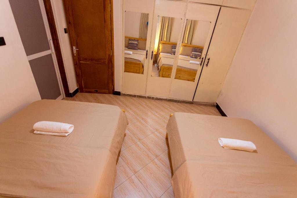 two beds in a small room with two mirrors at Nam's Homestay in Arusha