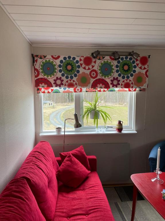 a red couch in front of a window with a flower curtain at Rosebo in Tranås
