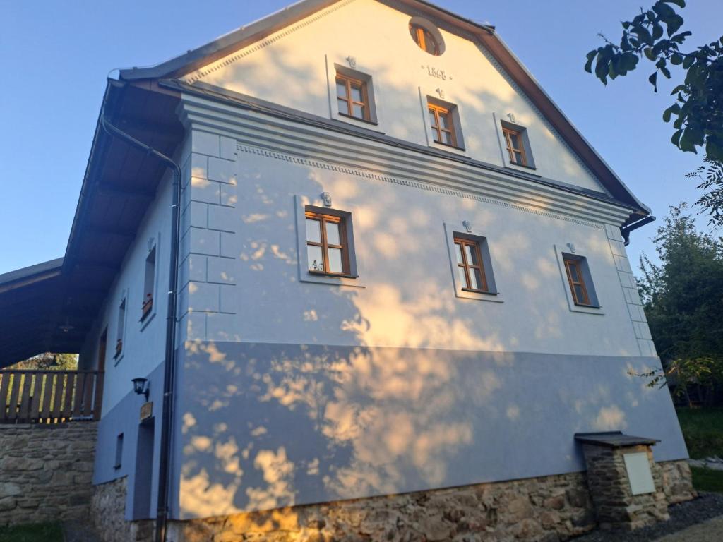 a white building with windows on the side of it at Sudetský grunt Autentická jesenická chalupa in Loučná nad Desnou