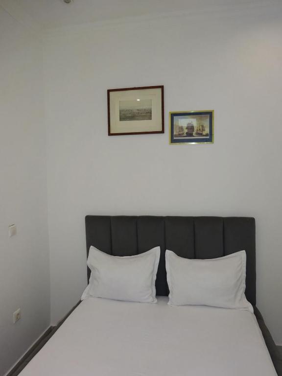 a bed in a room with two pictures on the wall at Room View boutique in Luanda