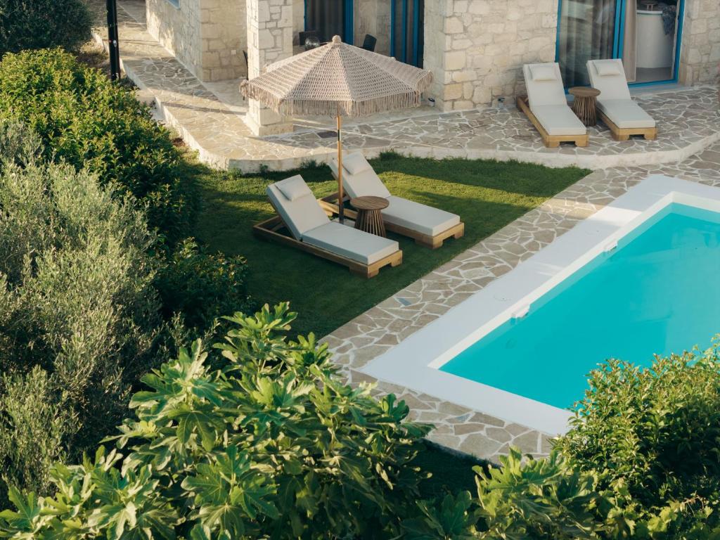 a pool with lounge chairs and an umbrella next to a house at Kyanorama Villa, A Seaside Escape in Tragaki
