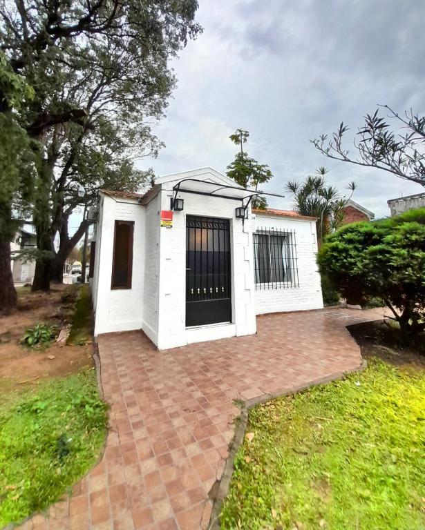 a white house with a black door on a brick driveway at Temporario La Marcela in Resistencia