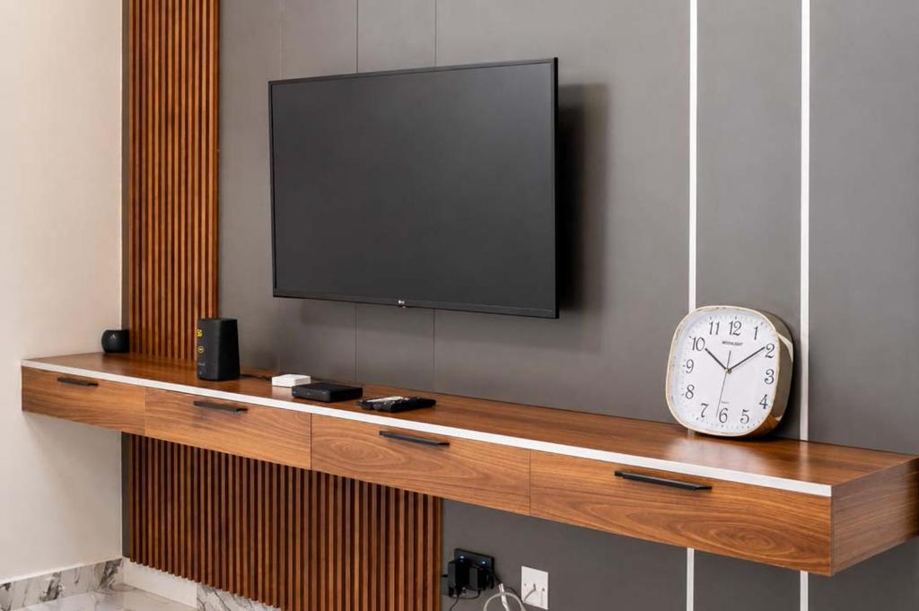 a television and a clock on a wooden shelf at Richgates Apartments in Enugu