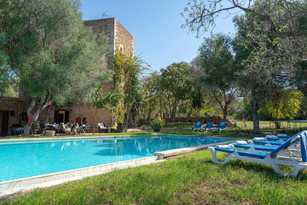 a swimming pool with blue lounge chairs in a yard at Finca Son Xona in Capdepera