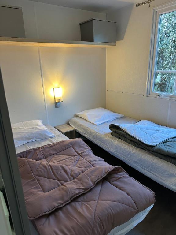 two beds sitting in a room with a window at camping les dolmens in Méjannes-le-Clap