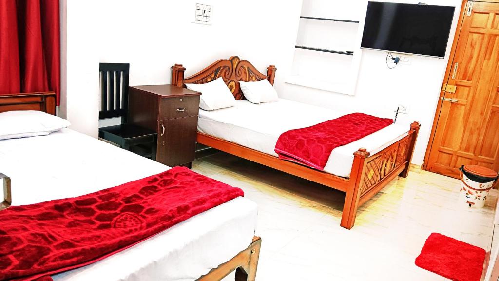 a hotel room with two beds with red sheets at Sri Ram Villa in Rāmeswaram