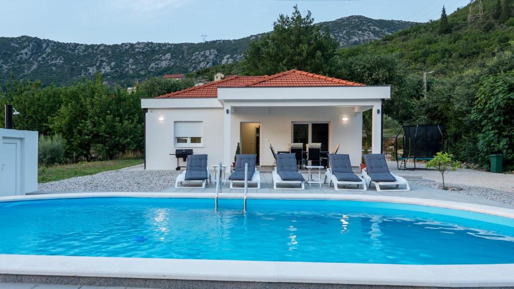 a swimming pool with chairs and a house at Villa Nature in Čapljina