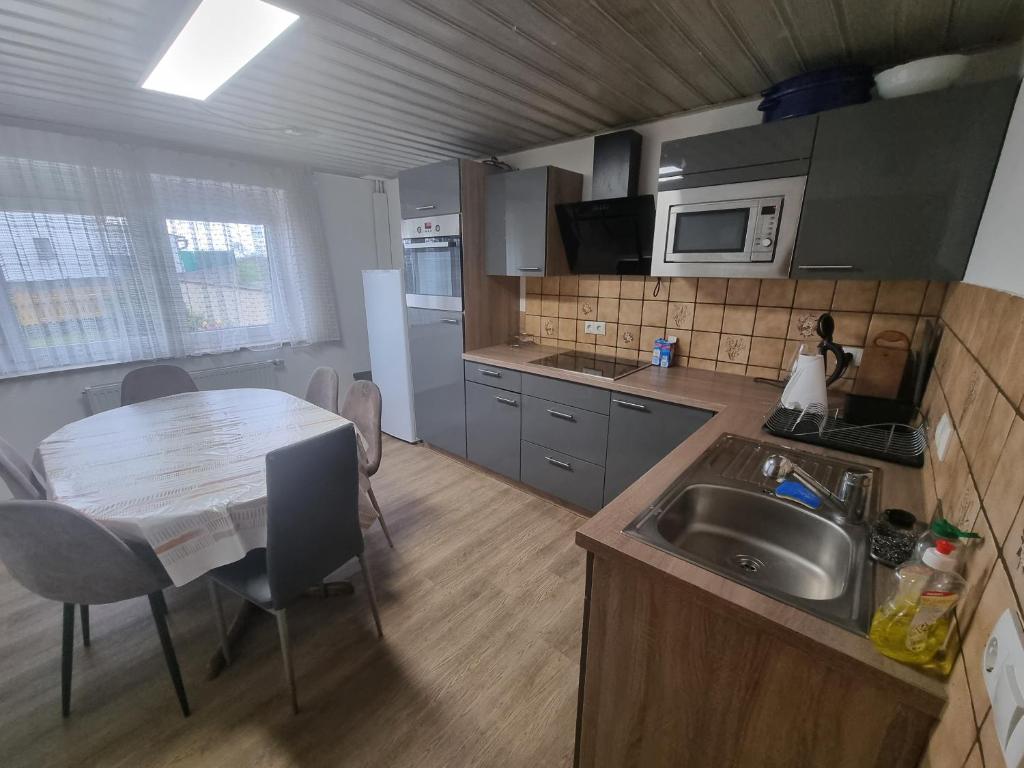 eine Küche mit einem Tisch und einer Spüle und einem Tisch und einer Küche mit in der Unterkunft D3 Haus in Feuchtwangen