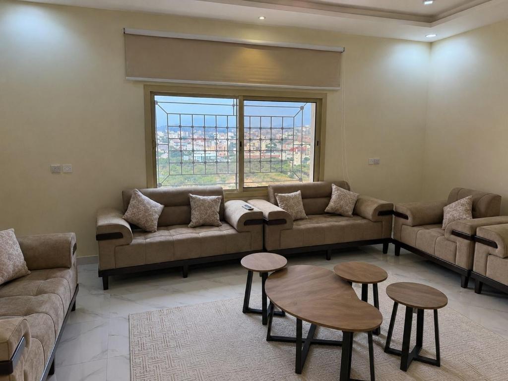 a living room with couches and tables and a window at Highland Residence Al namas in Lahbey