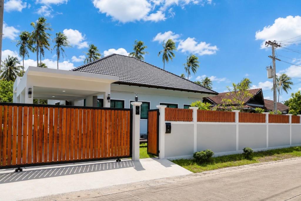 a house with a wooden fence at Sherlock Home Pool Villa Krabi in Ban Chong Phli