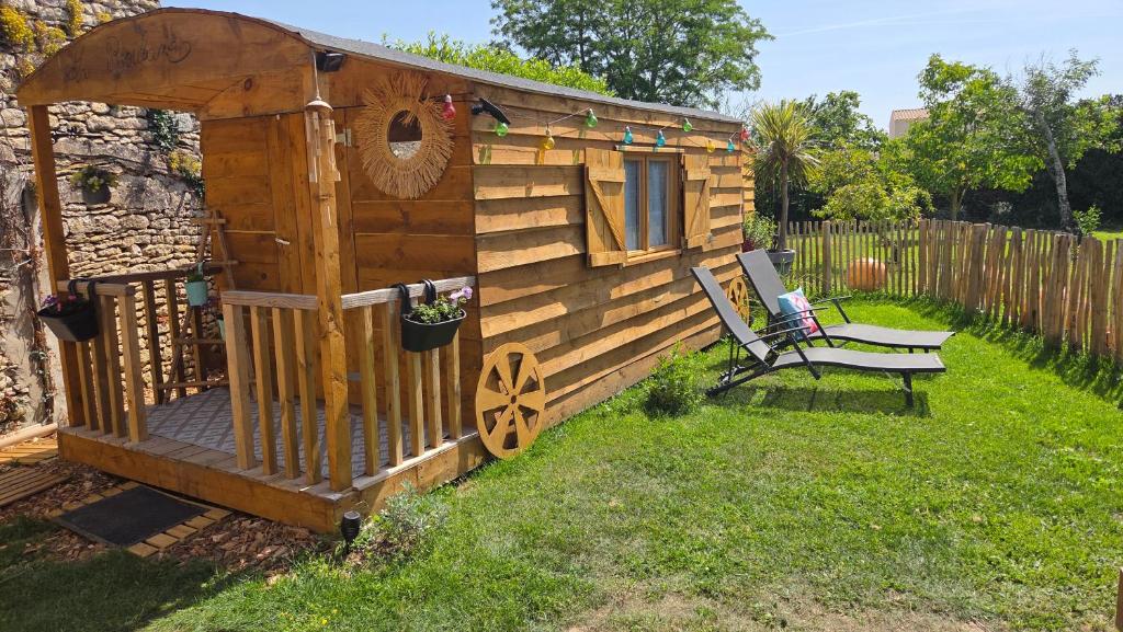 a wooden out house with a bench in a yard at Un aparté bohême "La Roubane" in Puyravault