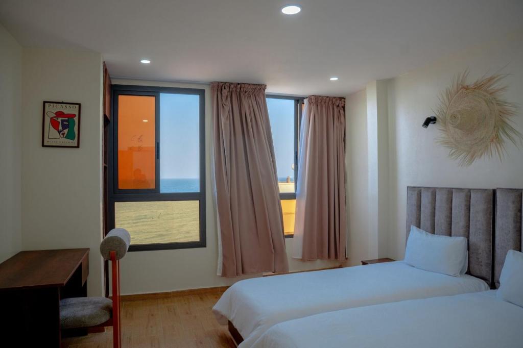 a hotel room with two beds and a window at Hola Rio in Dakhla