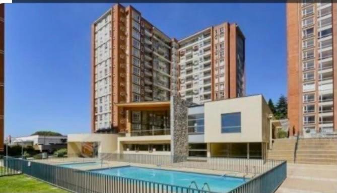 a large building with a swimming pool in front of it at Apart bio bio in Concepción