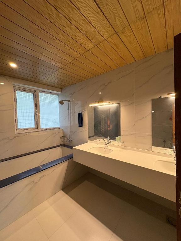 a large bathroom with two sinks and a mirror at The Elysian Villa in Murree