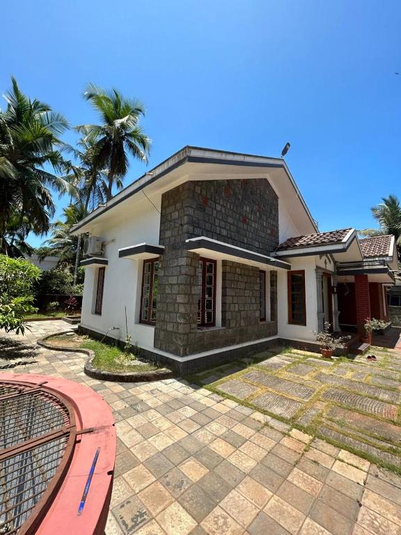 a white house with palm trees in front of it at DIVINE GRACE Homestay in Udupi
