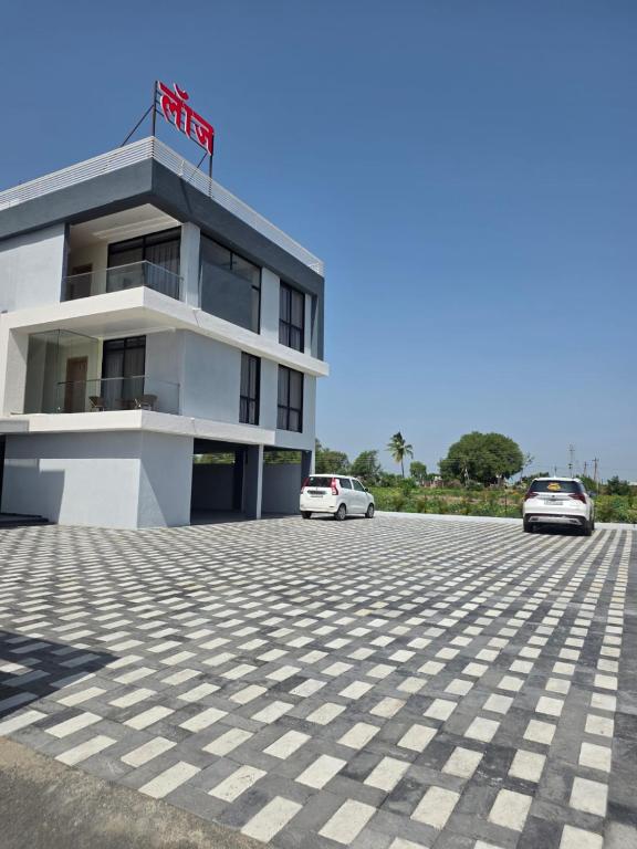 a building with two cars parked in front of it at Hotel Nandanwan Resto and Bar in Mālsiras