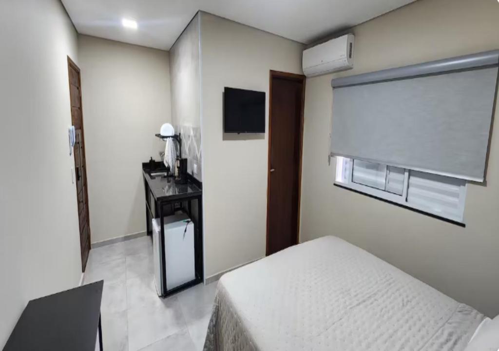 a bedroom with a bed and a desk and a television at Pousada Rainha da Serra in Espirito Santo Do Pinhal