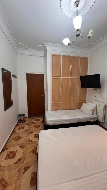 a room with two beds and a flat screen tv at Hotel islam 1 in Tlemcen