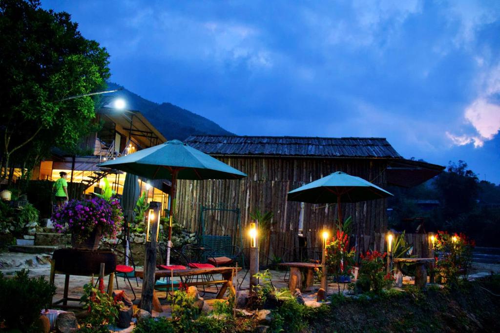 a patio with tables and umbrellas at night at Stilla Home in Tả Van