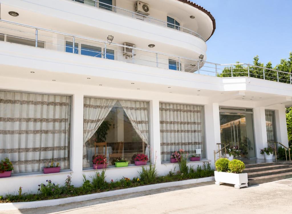 a large white building with windows and potted plants at Shtepia e Bardhe in Patos