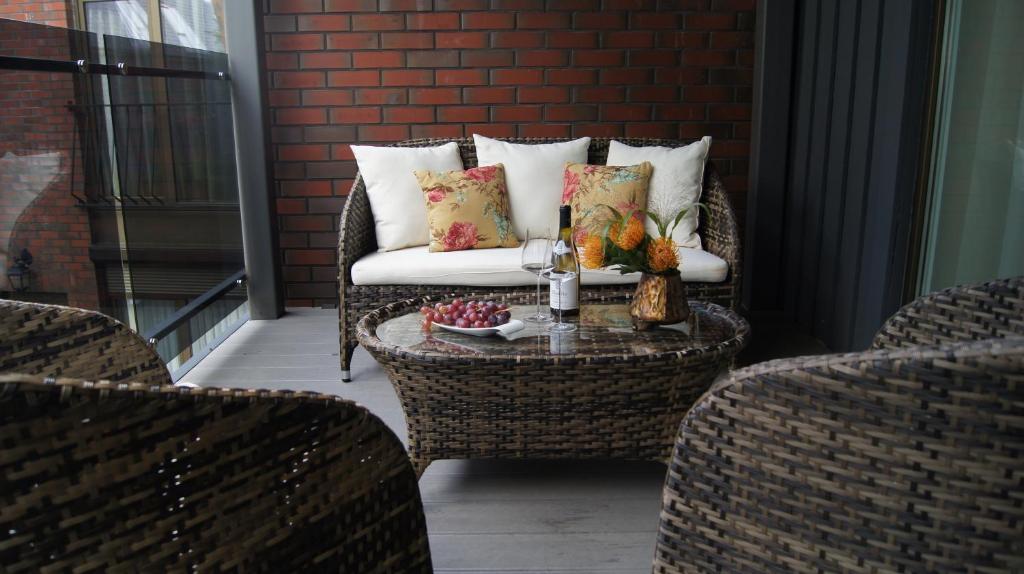 un patio con una silla de mimbre y una mesa con sofá en Vienaragio apartamentai, en Palanga