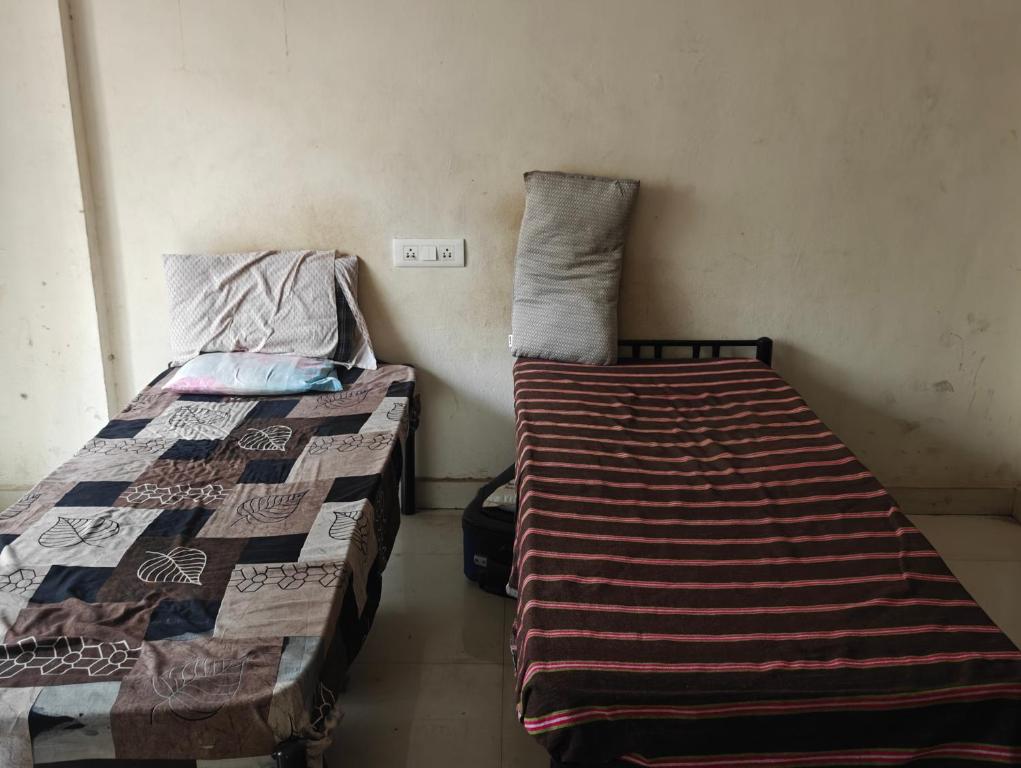 two beds sitting next to each other in a room at Shree Sai Ram PG in Pune