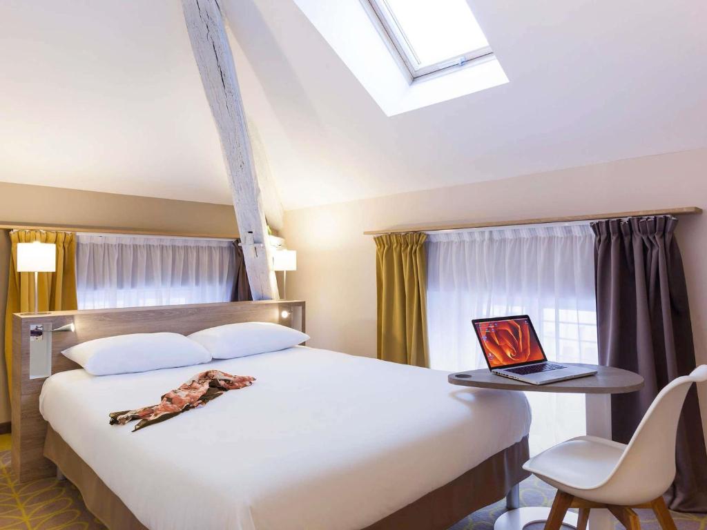 a bedroom with a bed with a laptop on a table at ibis Styles Chaumont Centre Gare in Chaumont