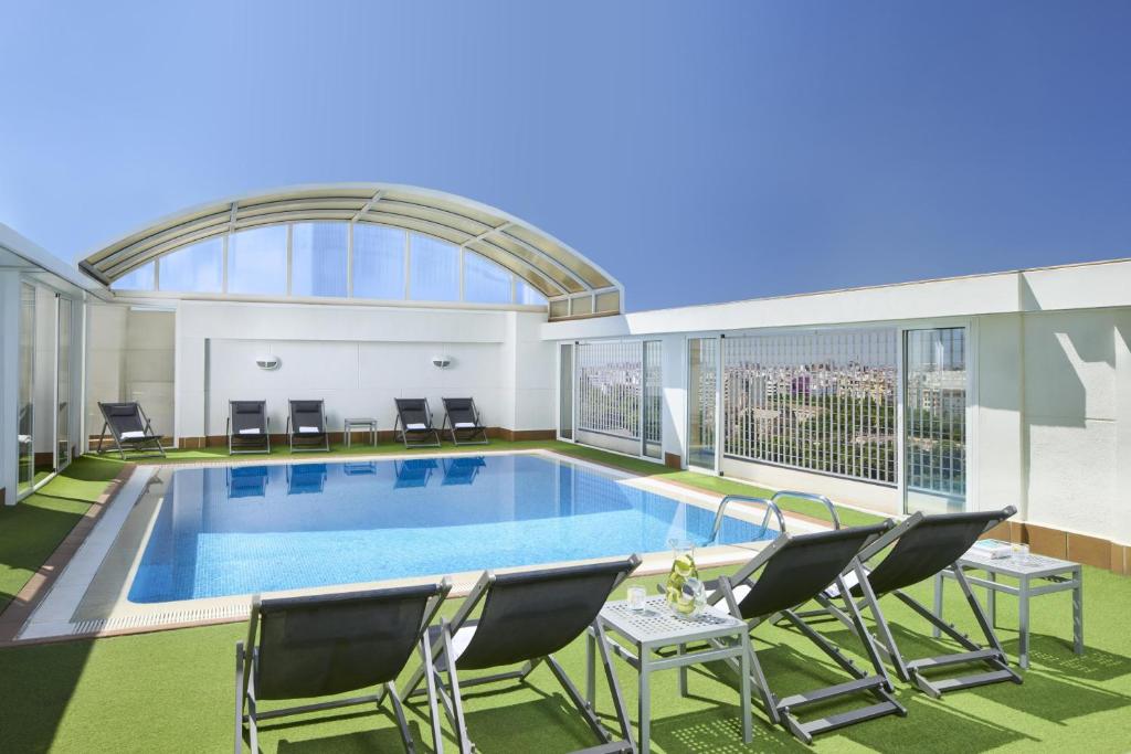 a large pool in a building with chairs at NH Valencia Center in Valencia