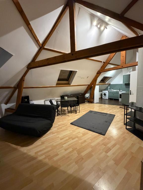 an attic room with a black couch on a wooden floor at Kimloge in Le Portel
