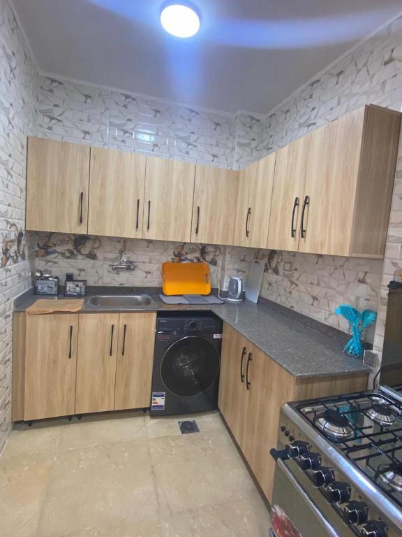 a kitchen with wooden cabinets and a washing machine at Ghazala valley ground floor in El Alamein