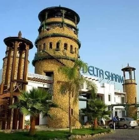 a building with a tower with a palm tree in front of it at فندق دلتا شرم in Sharm El Sheikh