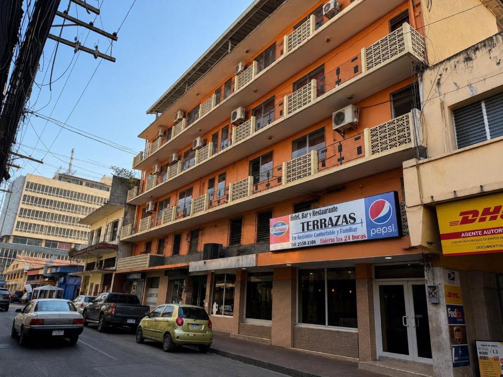 a building with cars parked on the side of a street at Hotel Terraza in San Pedro Sula