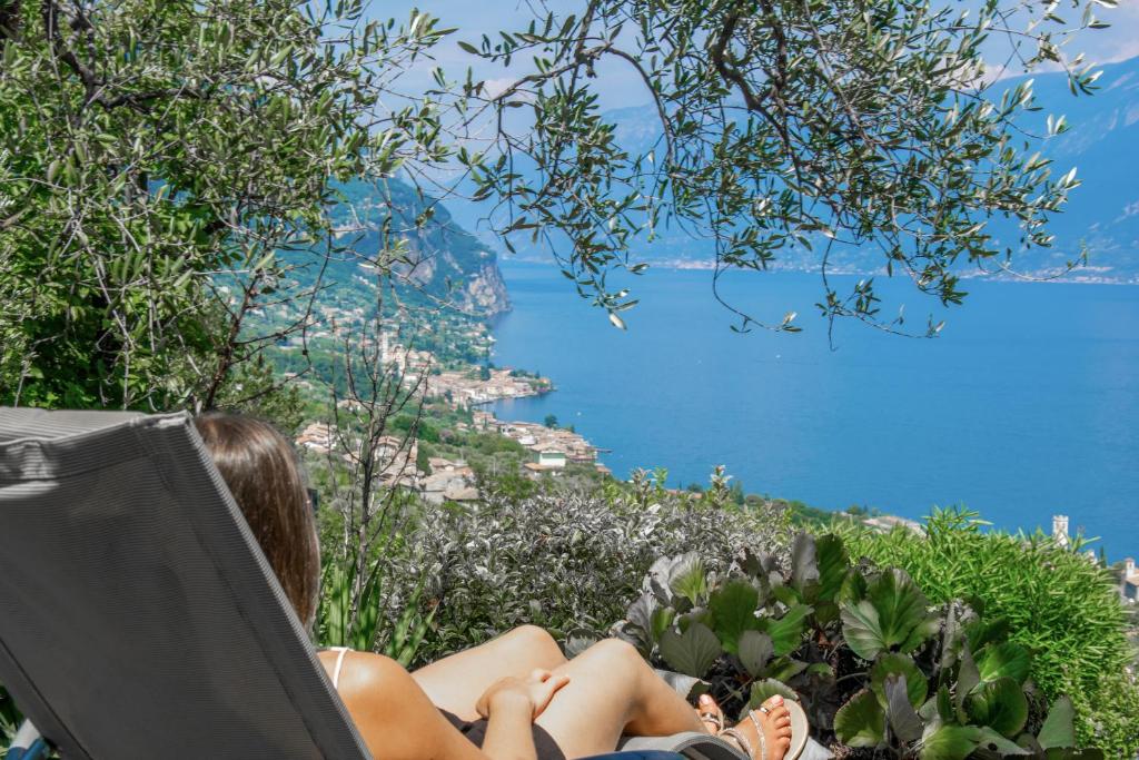 a woman laying in a chair looking at the water at Villa Supina - 3BDR with Pool & Panoramic Lake Garda Views in Toscolano Maderno