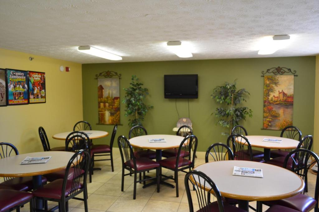 a dining room with tables and chairs and a flat screen tv at Baymont by Wyndham Pigeon Forge near Island Drive in Pigeon Forge