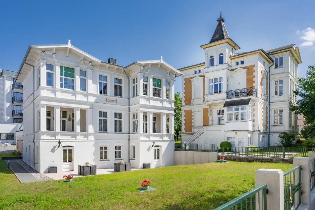 a large white building with a grassy yard at Villa Tanneck App 1 in Ahlbeck