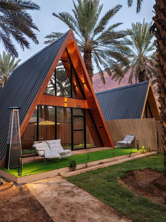 a house with a gambrel roof and two chairs at كوخ ساره سبيشل دورين in Al-ʿUla