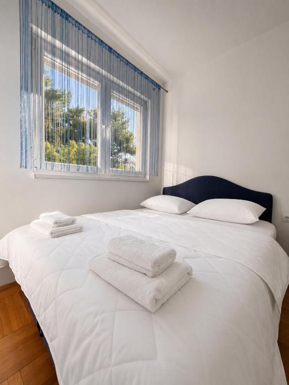 a white bed with two towels on top of it at Apartman Centar Agrokop in Trebinje