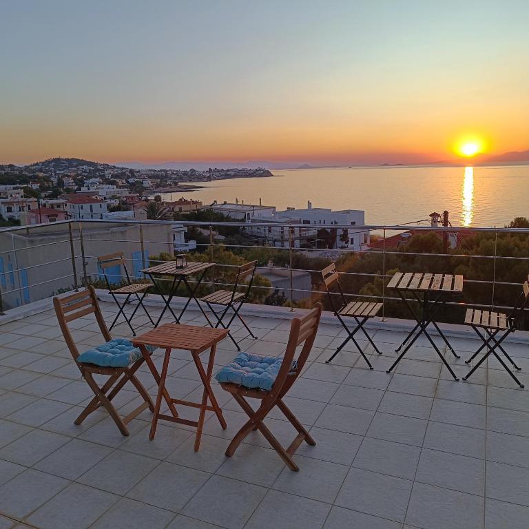 a table and chairs on a roof with the sunset at Schinos Salty Studio in Vathí