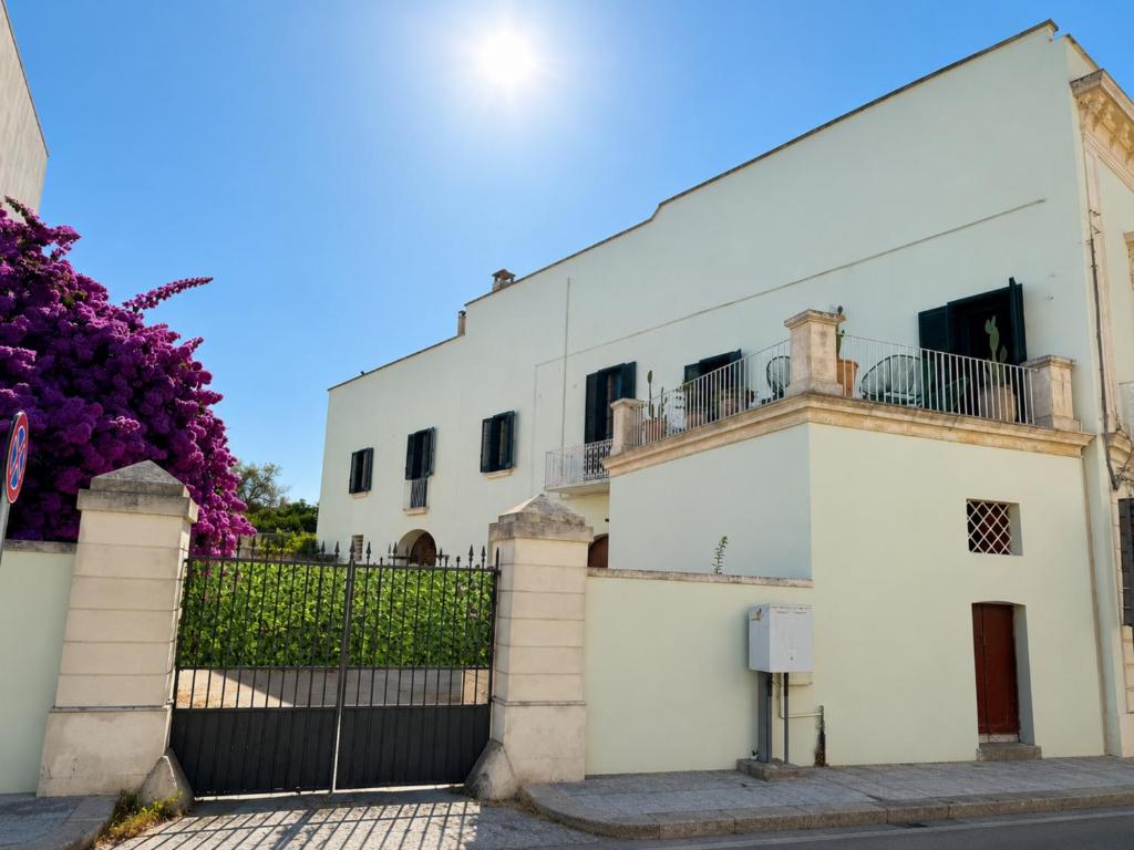 a white house with a fence and purple flowers at Palazzo Vite in Copertino
