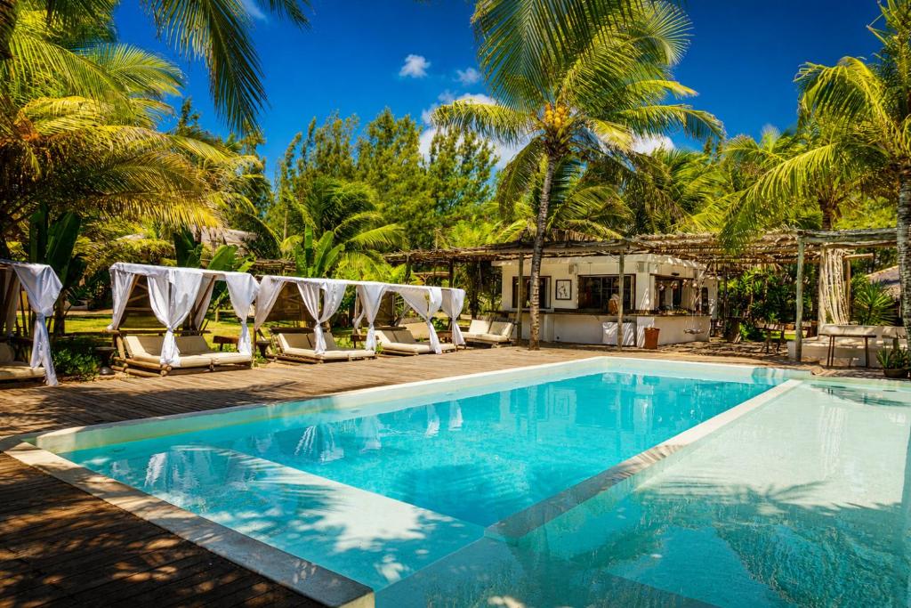a pool with lounge chairs and palm trees at Zebra Boutique Hotel in Beberibe