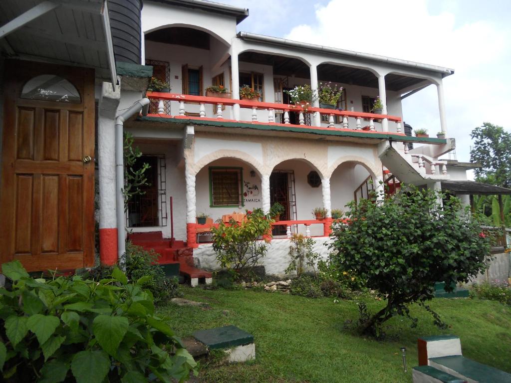 ein großes weißes Haus mit einer Veranda und einer Tür in der Unterkunft Drapers San Guest House in Port Antonio