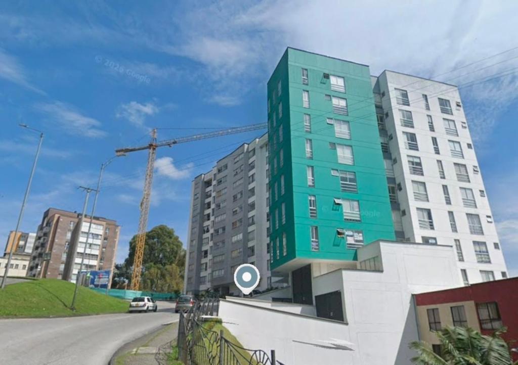 a tall green building on the side of a street at Confortable apartaestudio in Manizales