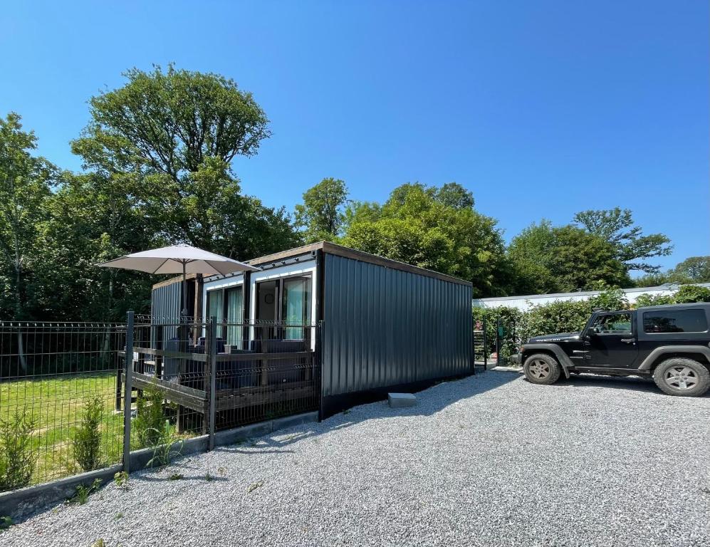 a black tiny house with an umbrella and a truck at Maison familiale in Froid-Chapelle