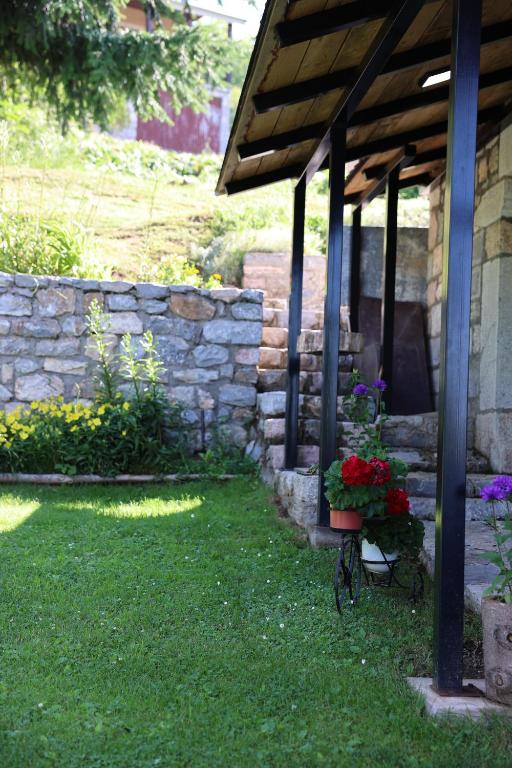 eine Terrasse mit Steinmauer und Blumen im Garten in der Unterkunft Baba I Dede in Galičnik
