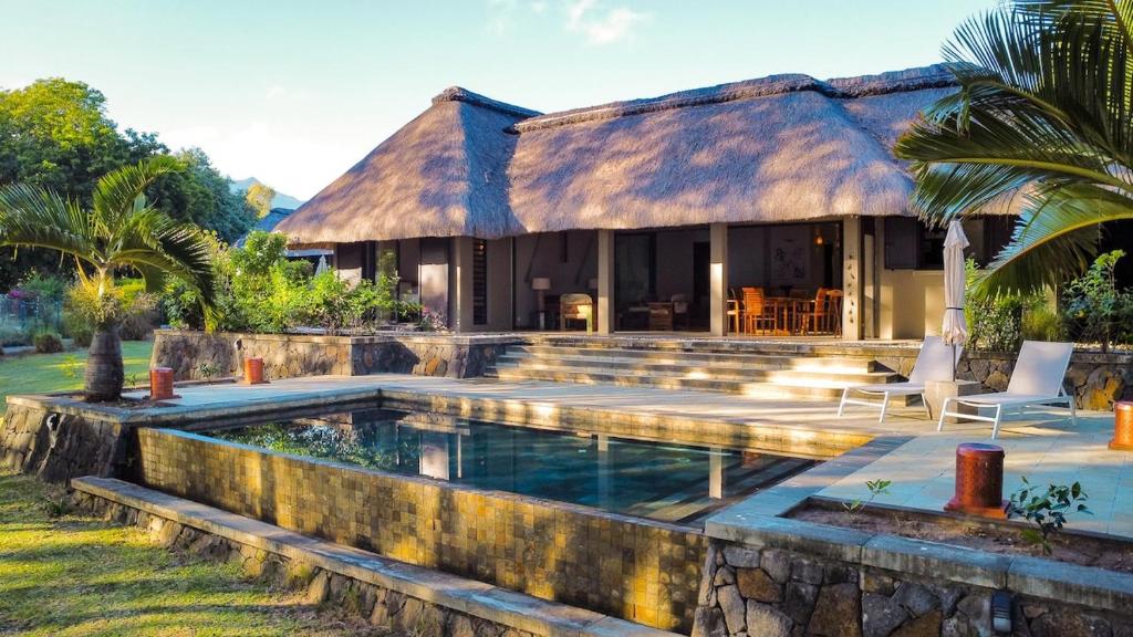 a house with a swimming pool in front of it at Beachfront Villa with Pool & Sunset Views in Rivière Noire