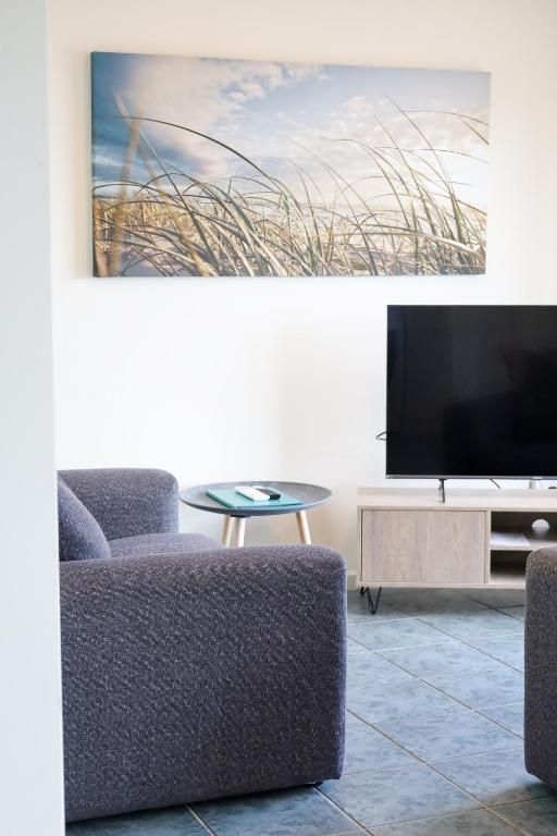 a living room with a couch and a tv and a table at Robe Sunset Apartments in Robe